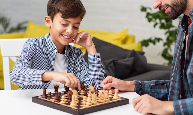 Happy son playing chess with his father