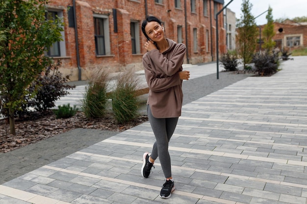 Happy sporty woman in earphones posing in the middle of the street