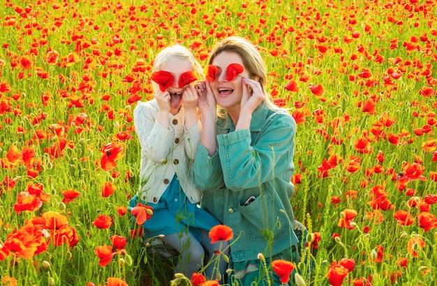 Photo happy spring family mother and daughter hugging in a poppies meadow mom and child girl resting in the field with poppy flowers the woman and girl have fun and enjoy the freedom