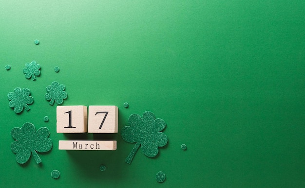 Happy St Patrick's Day decoration concept made from shamrocks clover leaf wooden calendar and leprechaun hat on green background