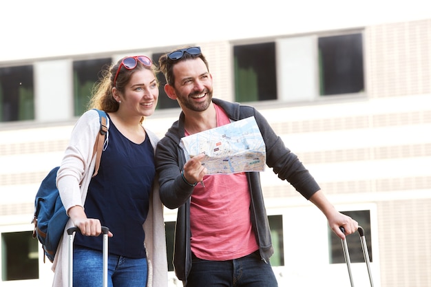 Happy standing in city with luggage and tourist map