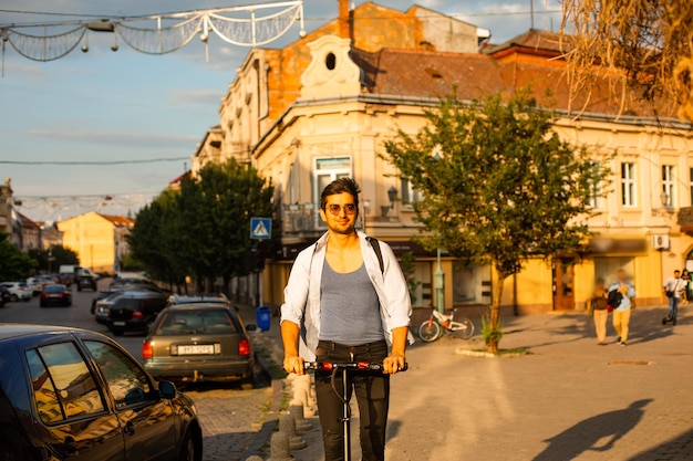 The happy student rides an electric scooter in the city