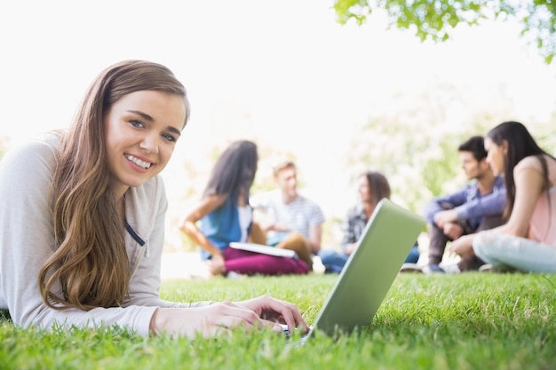 Happy student using her laptop outside