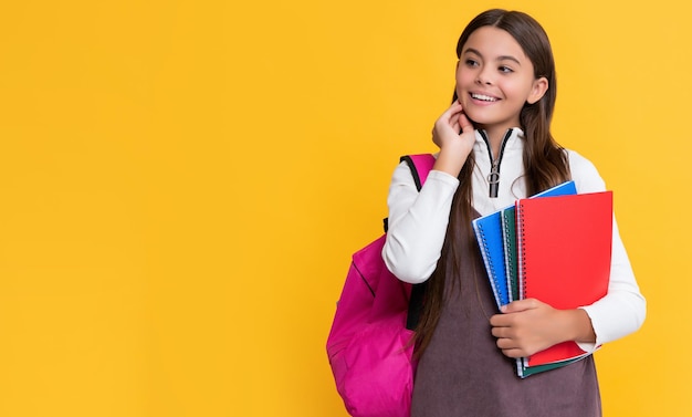 Happy student with school backpack and workbook on yellow background