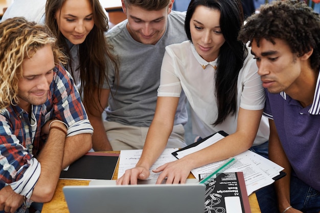 Happy students and working together on laptop in classroom assignment and online project in university Scholarship typing and collaboration in college by computer and blog for academic research