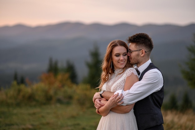 Happy stylish bride and groom running and having fun in mountains on summer sunny day