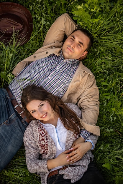 Happy stylish couple lying in green grass