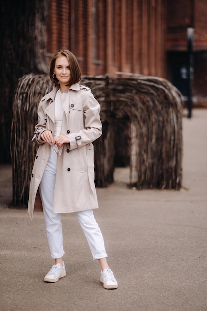 A happy stylish girl in a gray coat walks around the city