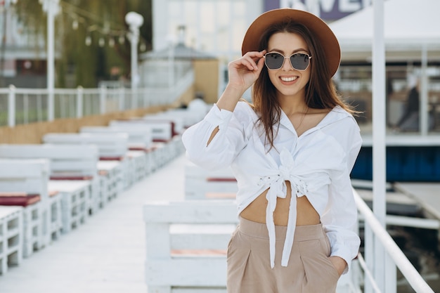 A happy stylish woman walks along the beachfront on a warm summer day in the sunset