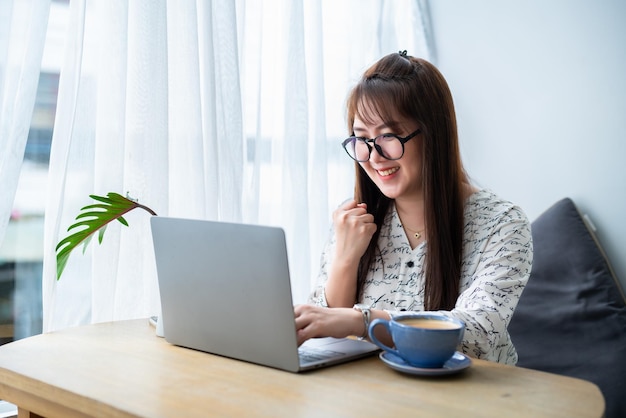 Happy successful business of asian freelance people business female expressed confidence embolden working with laptop computer with coffee cup and smartphone in coffee shop communication concept