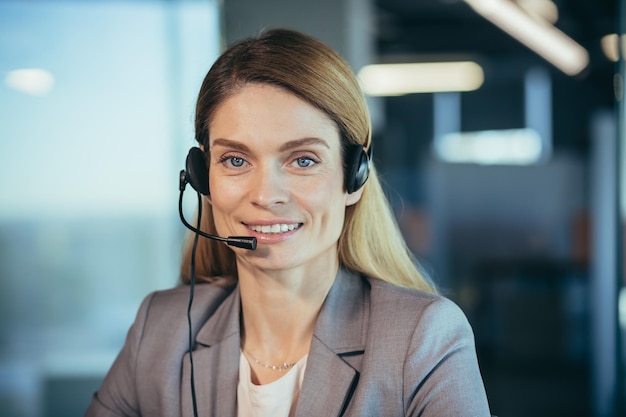 Happy and successful business woman looking at camera and smiling female worker with headset for video call close up portrait