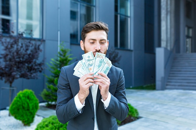 Happy successful Caucasian bearded businessman counts, waves, throws, show off, flaunt cash money background a modern office building looking at camera Celebrate Winner success in betting stock market