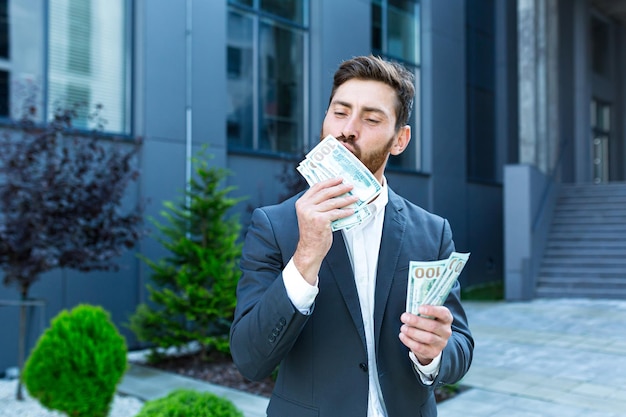 Happy successful Caucasian bearded businessman counts, waves, throws, show off, flaunt cash money background a modern office building looking at camera Celebrate Winner success in betting stock market