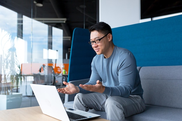 Happy and successful freelancer business man working from office asian man having fun talking on video call looking at webcam