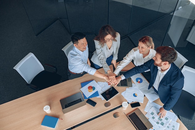 Happy successful multiracial business team showing unity with their hands