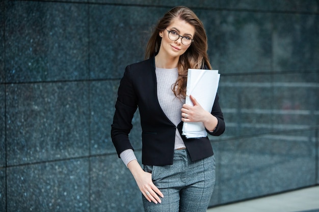 Happy successful professional woman posing near office building