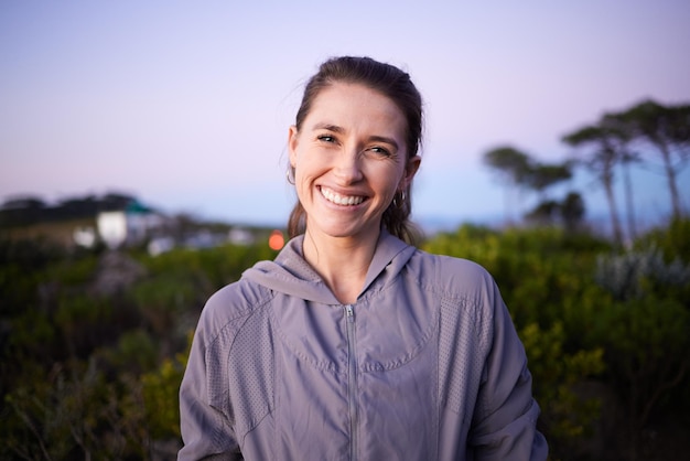 Happy sunset and portrait of a woman in a park during dusk for peace calm and zen Adventure hike and face of a girl on a walk for fitness summer cardio and relaxing during dawn in nature