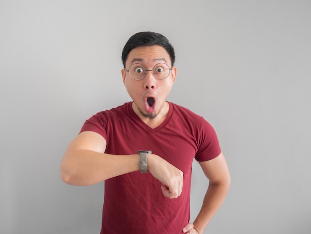 Happy and surprised Asian man who is looking at his watch.