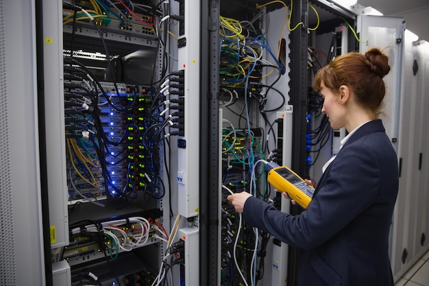 Happy technician using digital cable analyzer on server 