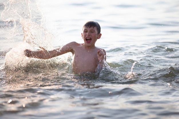 Happy teen boy plays with sea waves The boy swims in the sea