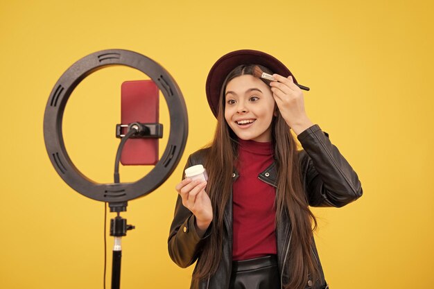 Happy teen girl blogger use selfie led lamp and smartphone on tripod blog