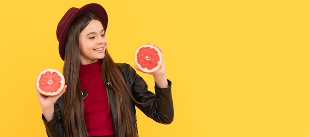 Happy teen girl in hat and leather jacket hold cut grapefruit Child girl portrait with grapefruit orange horizontal poster Banner header with copy space