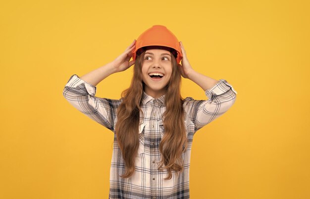 Photo happy teen girl in helmet and checkered shirt carpenter