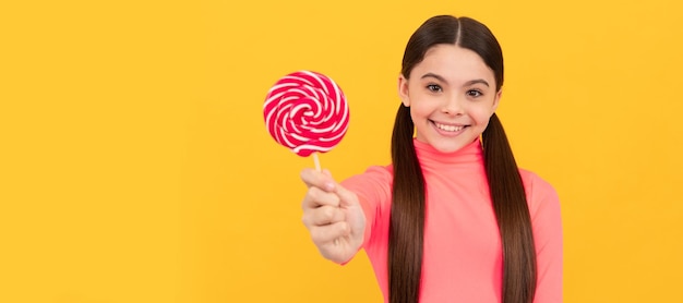 Photo happy teen girl with lollipop candy on stick on yellow background candy shop teenager child with sweets poster banner header copy space