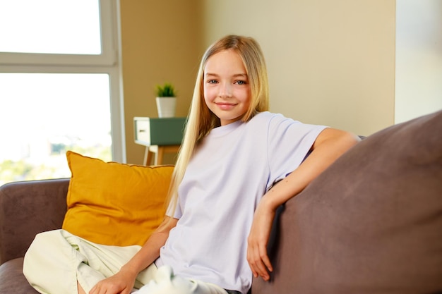 Happy teenage girl cotton tshirt sitting on sofa at home