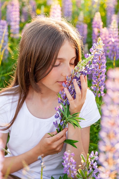 Happy teenage girl smiling outdoor. Beautiful young teen woman resting on summer field with blooming wild flowers green background. Free happy kid teenager girl, childhood concept