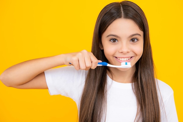 Happy teenager portrait closeup Funny teen girl brush her teeth dental healthy concept isolated over yellow background Healthy kids teeth Oral medical and stomatology concept Smiling girl