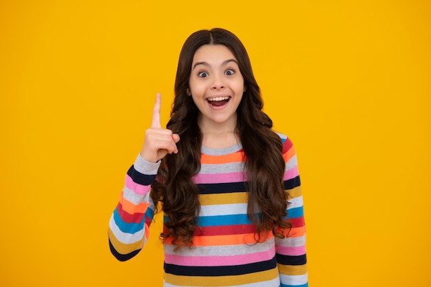 Happy teenager positive and smiling emotions of teen girl Excited teenager girl opening mouth in excitement believe big sale or promo on yellow studio background copy space