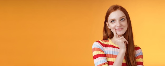 Happy tender feminine redhead 20s girl university student smiling delighted dreaming tasty slice pizza touching lip thoughtful thinking daydreaming look upper left corner imaging desires