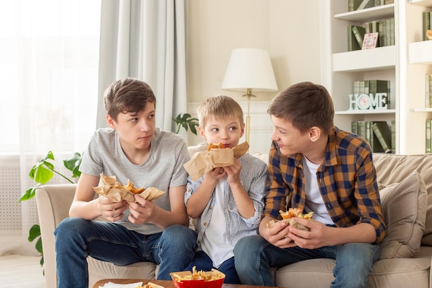 A happy three teenage boys eating fast food in living room