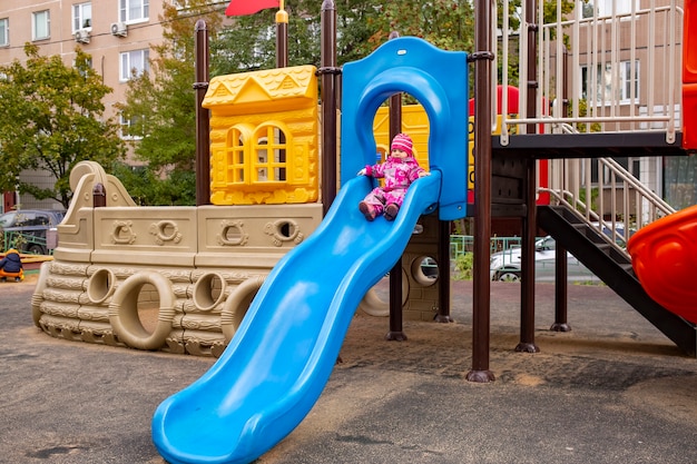 Happy toddler boy playing on a slide at a playground