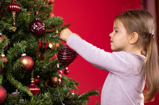 happy toddler girl decorating Christmas tree