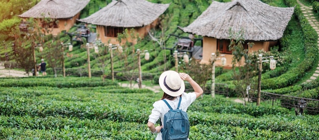 Happy tourist woman in white dress enjoy beautiful Tea gardenTraveler visiting in Ban Rak Thai village Mae Hong Son Thailand travel vacation and holiday concept