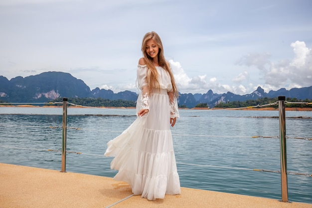 Happy travel girl fun on wooden pier with lake rainforest jungle and mountains