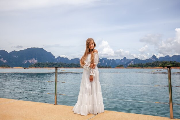 Happy travel girl fun on wooden pier with lake rainforest jungle and mountains