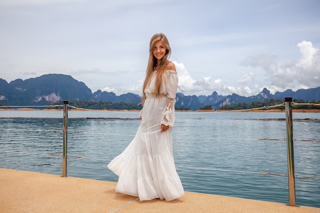 Happy travel girl fun on wooden pier with lake rainforest jungle and mountains