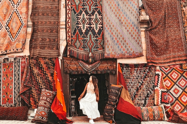 Happy travel woman with amazing colorful carpets in Local carpet shop ,Goreme. Cappadocia Turkey