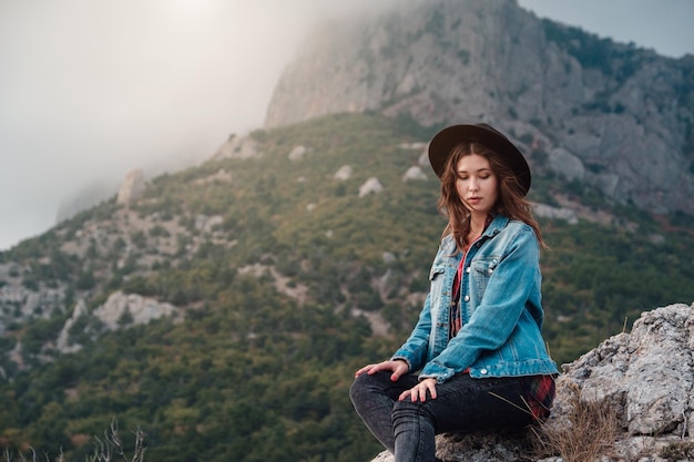 Happy traveler hipster girl on top of cloudy mountains