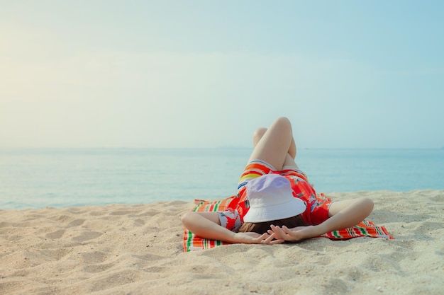 Happy traveller woman in red dress enjoys her tropical beach vacation