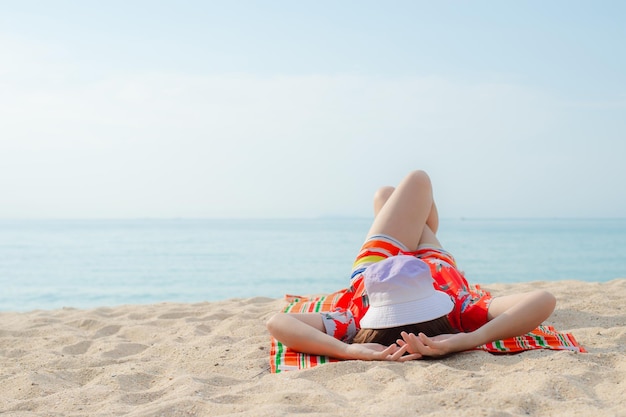 Happy traveller woman in red dress enjoys her tropical beach vacation