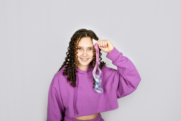 Happy trendy curly teenager girl with colored dyed hair young hipster on pastel background