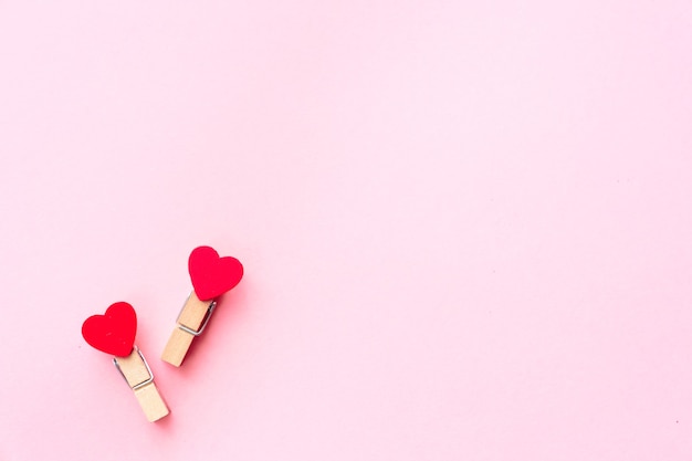 Happy valentines day 2021. Two clothespin with hearts on a pink sheet of paper. Postcard.