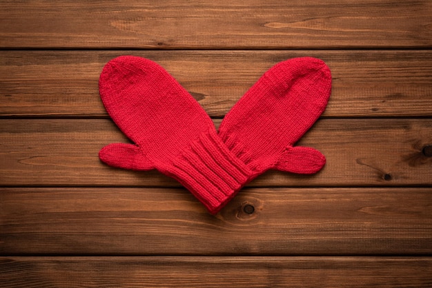 Happy valentines day card with red heart folded from mittens on vintage wooden background