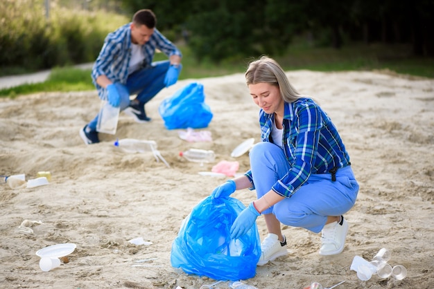 Happy volunteers with garbage bags cleaning area in park