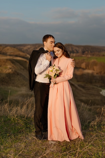 Happy wedding couple admire the beautiful landscape at sunset.