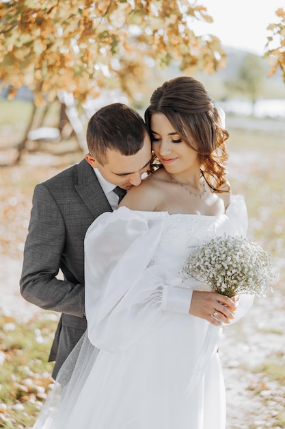 Happy wedding couple in the countryside A beautiful bride and a stylish groom He kisses her should